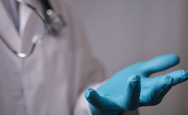 A closeup shot of a doctor in medical blue gloves holding his hand forward - Foto, immagini
