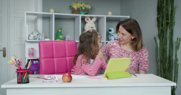 Distance learning online education. Schoolgirl with digital tablet doing school homework. Mom does homework with her daughter at home. - Séquence, vidéo