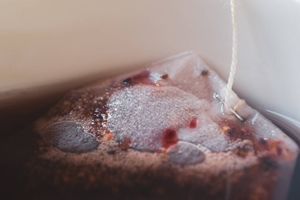 A closeup shot of a teabag in the white cup of tea - Photo, Image