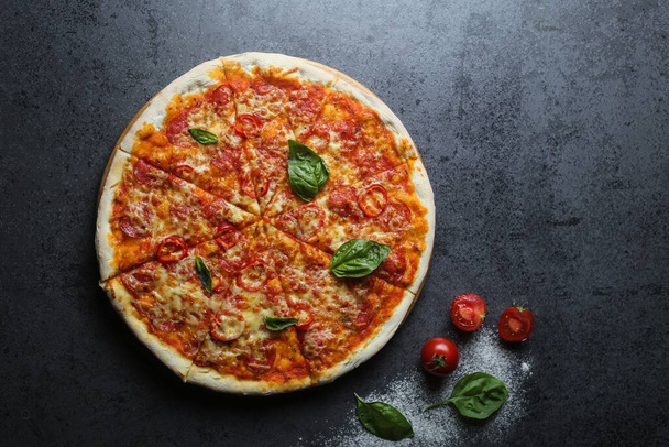 A top view of a delicious pizza with tomatoes and basil on a table - Foto, Imagem