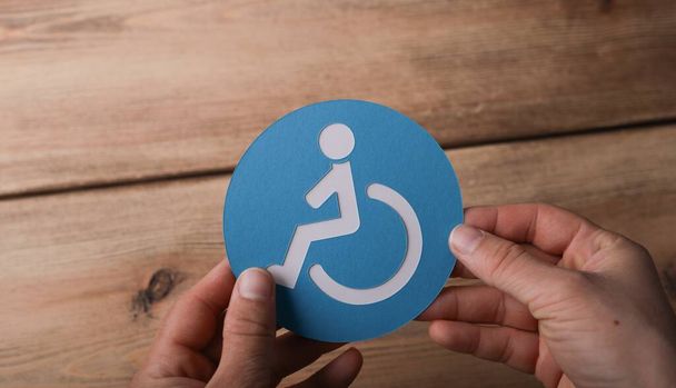 A high angle shot of a man holding a blue and white wheelchair symbol - Φωτογραφία, εικόνα