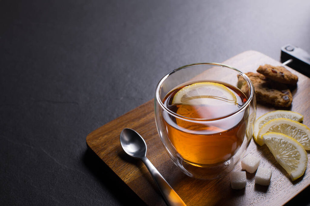 Egy csésze tea citrommal fekete gránit háttéren - Fotó, kép