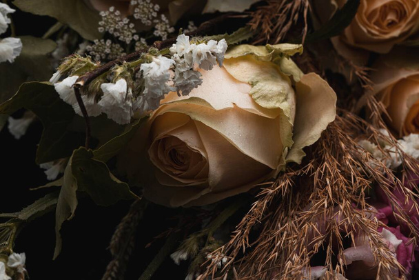 A closeup shot of a luxurious bouquet of orange roses and white flowers on a black background - Fotó, kép