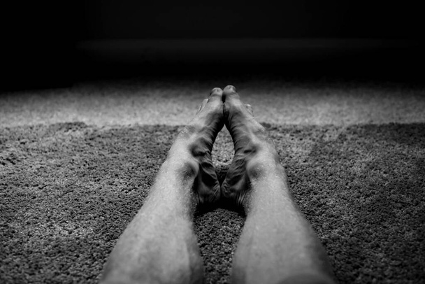 A greyscale shot of the feet of a man on the soft rug on the floor - Valokuva, kuva