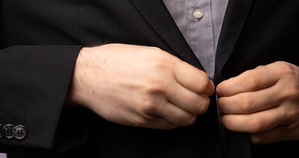 The hands of a businessman buttoning up his black suit - Fotó, kép