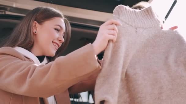 Attractive girls have shopped and checking purchases at the car back - Video