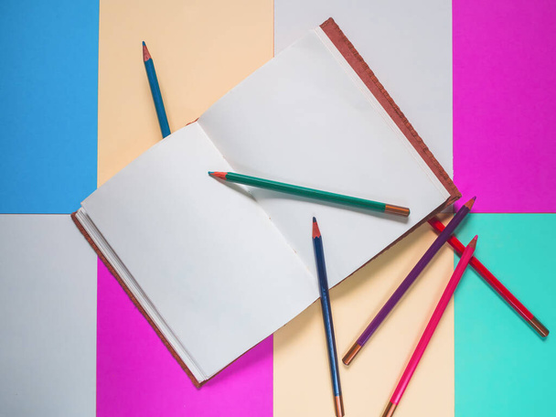 Σημειωματάριο σε φόντο χρώματος και συλλογή μολυβιών χρώματος - Φωτογραφία, εικόνα