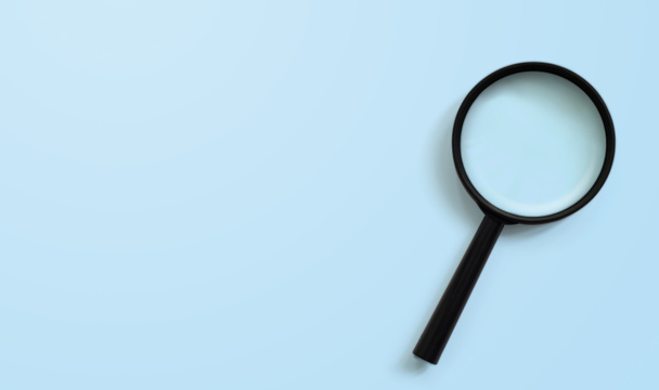 Magnifying glass on blue colour background with copy space. Searching information data concept - Photo, Image