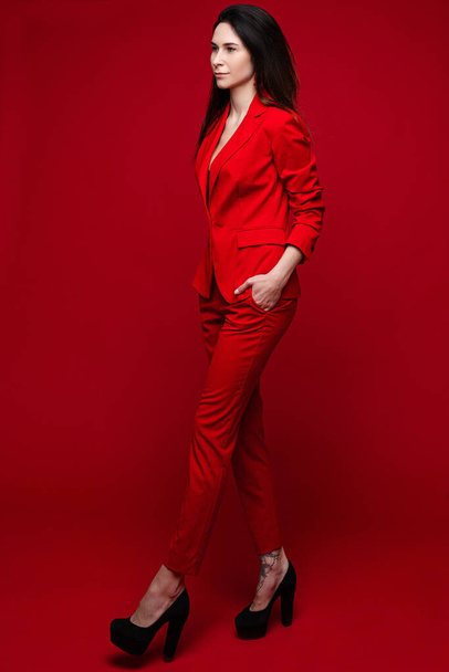 Mujer encantadora posa para la revista de la oficina, imagen aislada sobre fondo rojo
 - Foto, Imagen