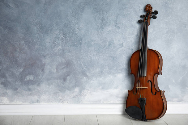 Classic violin on floor near grey wall. Space for text - 写真・画像