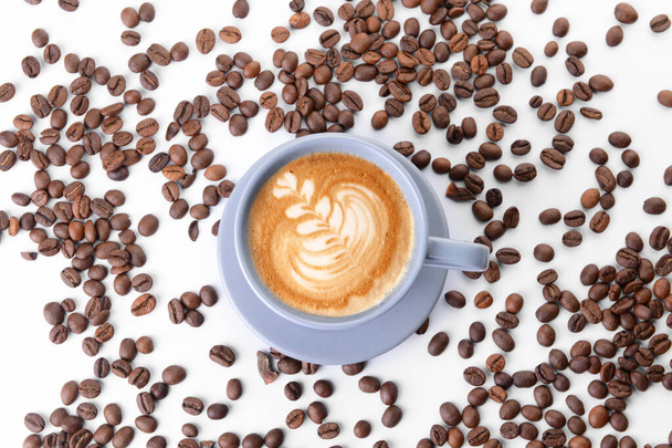 Cup of tasty cappuccino and coffee beans on white background - Photo, image