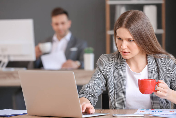 Giovane donna che beve caffè mentre lavora in ufficio
 - Foto, immagini