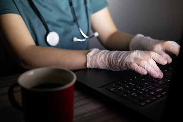 Doctor or nurse's hands on keyboard in the dark. Long hours or overtime work of medical worker concept. - Photo, Image