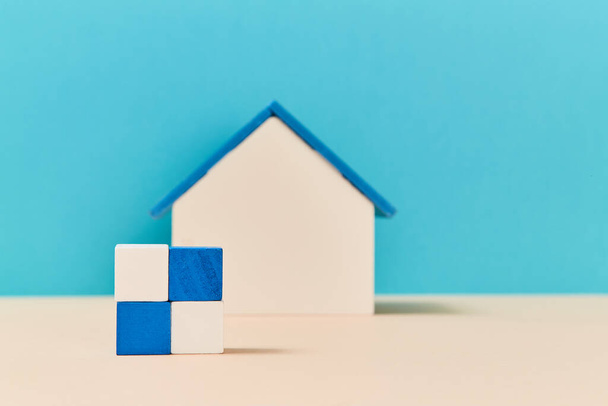 Model of house miniature on blurred background. Square of wooden cubes in white, blue colours. Mockup style. Copy space - Fotó, kép