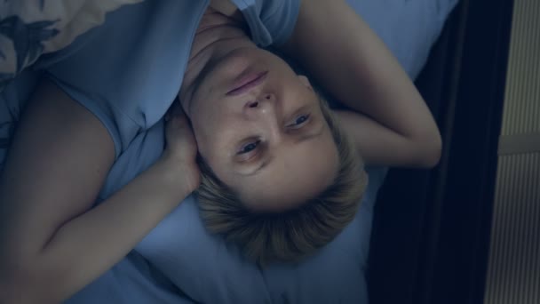 vertikal. eine an Schlaflosigkeit leidende Frau liegt mit offenen Augen im Bett. - Filmmaterial, Video