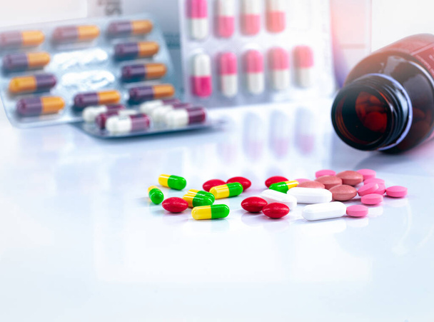 Värikkäitä tabletteja ja kapseli pillereitä hämärtynyt taustalla lääkepullo ja antibiootti kapseli pillereitä. Lääketeollisuus. Raskaana olevien naisten ja vanhusten huumeidenkäytön sisältö. - Valokuva, kuva