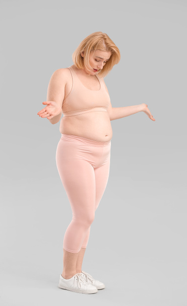 Troubled overweight woman on grey background - Foto, afbeelding