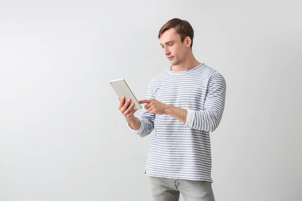 Young man with tablet computer on light background - Photo, image