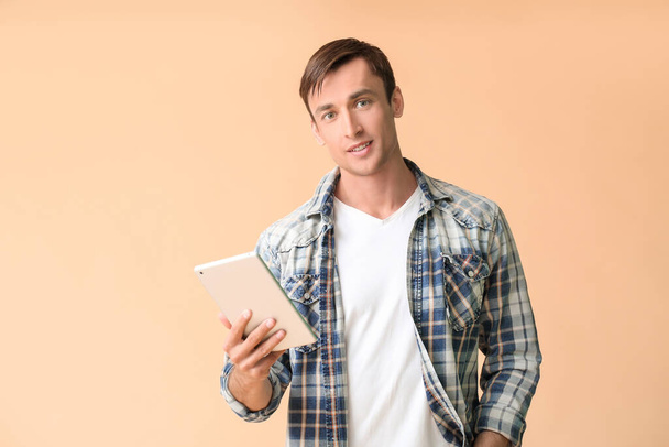 Junger Mann mit Tablet-Computer auf farbigem Hintergrund - Foto, Bild
