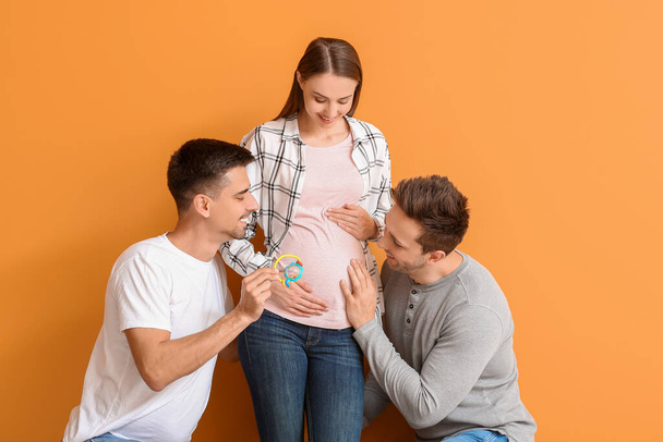 Гей пара с беременной женщиной на цветном фоне
 - Фото, изображение