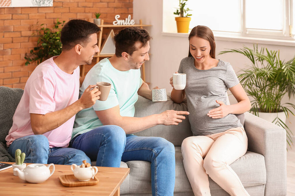 Schwules Paar mit schwangerer Frau trinkt Tee zu Hause - Foto, Bild