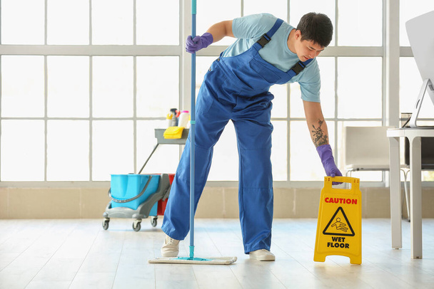Muž údržbář drhnutí podlahy v kanceláři - Fotografie, Obrázek