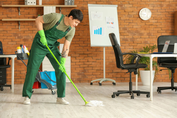Άντρας επιστάτης σφουγγαρίζει πάτωμα στο γραφείο - Φωτογραφία, εικόνα