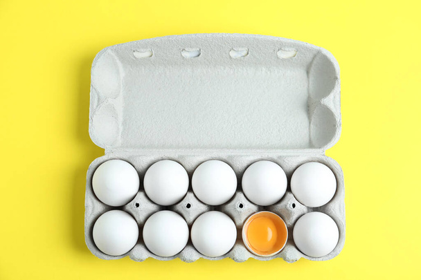 Fresh chicken eggs in box on yellow background, top view - Foto, imagen