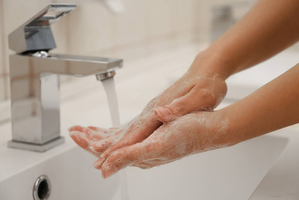 Woman washing hands with antiseptic soap in bathroom, closeup. Virus prevention - Photo, image
