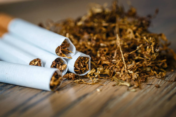 gesneden tabaksbladeren en handgemaakte sigaretten op een houten ondergrond - Foto, afbeelding