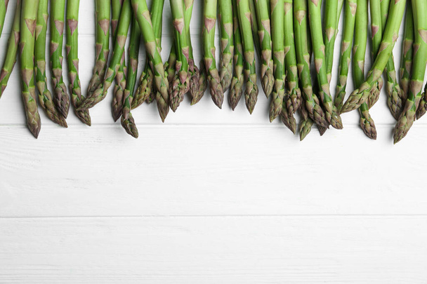 Fresh raw asparagus on white table, flat lay. Space for text - Photo, image