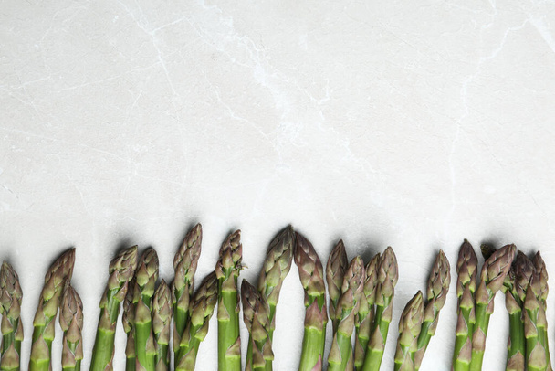 Fresh raw asparagus on light grey marble table, flat lay. Space for text - Photo, image
