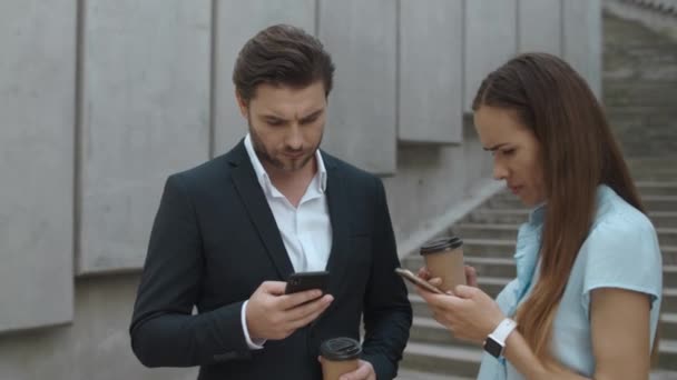 Επιχειρηματίες που χρησιμοποιούν smartphones στο δρόμο. Άντρας και γυναίκα πίνουν καφέ για να φύγουν. - Πλάνα, βίντεο