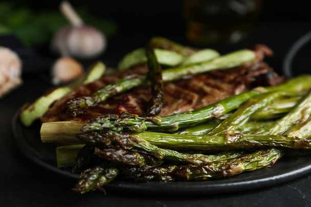 Tasty asparagus with grilled meat on slate board, closeup - Фото, зображення