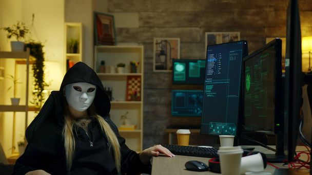 Hacker girl wearing a white mask to hide her identity - Zdjęcie, obraz