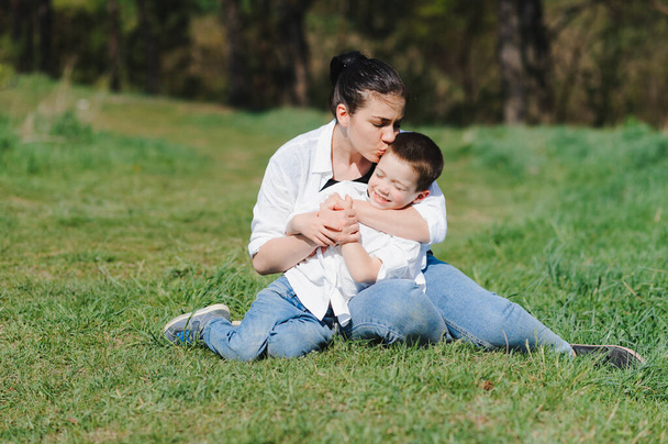 Szczęśliwa młoda matka bawi się ze swoim dzieckiem w parku na zielonym trawniku. Szczęście i harmonia życia rodzinnego. Wspaniałe rodzinne wakacje. Dobry weekend. Dzień Matki. Wakacje. Koncepcja szczęśliwej rodziny. - Zdjęcie, obraz