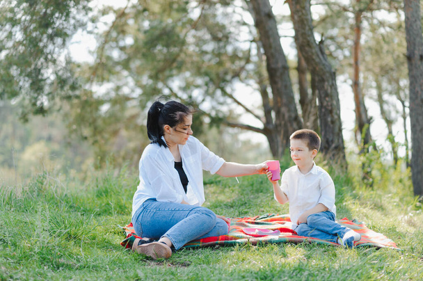 Счастливая молодая мама играет со своим ребенком в парке на зеленой лужайке. Счастье и гармония семейной жизни. Отличный семейный отдых. Хороших выходных. День Матери. Праздник. Концепция счастливой семьи
. - Фото, изображение