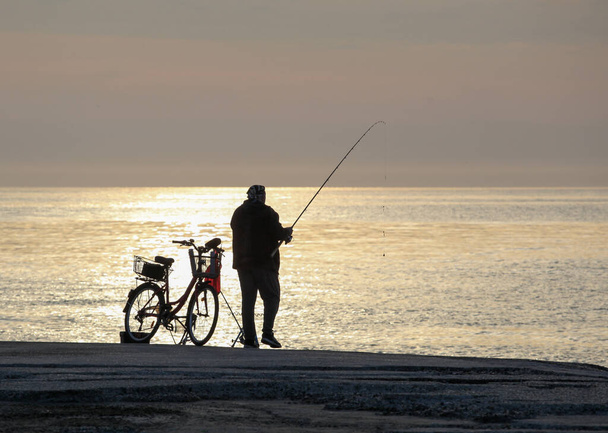 Pomorie, Bulgaria - May 11, 2020: A fisherman on the beach catches fish early in the morning - Fotó, kép
