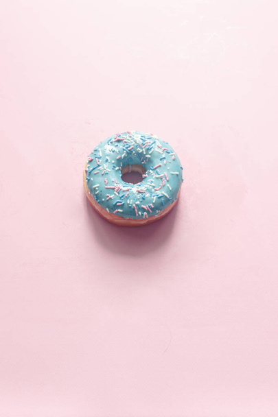 close-up view of donut with bubblegum flavor with frosted and filled with fruit jam and cream, colored glazed and sprinkled donuts on pink background - Photo, Image