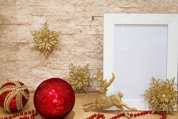 Kerst mock up. Wenskaart, gouden hert en sneeuwvlok, rode kralen, rode en gouden kerstballen en bakstenen muurachtergrond. Begrepen, ruimte. Kerstversiering.  - Foto, afbeelding