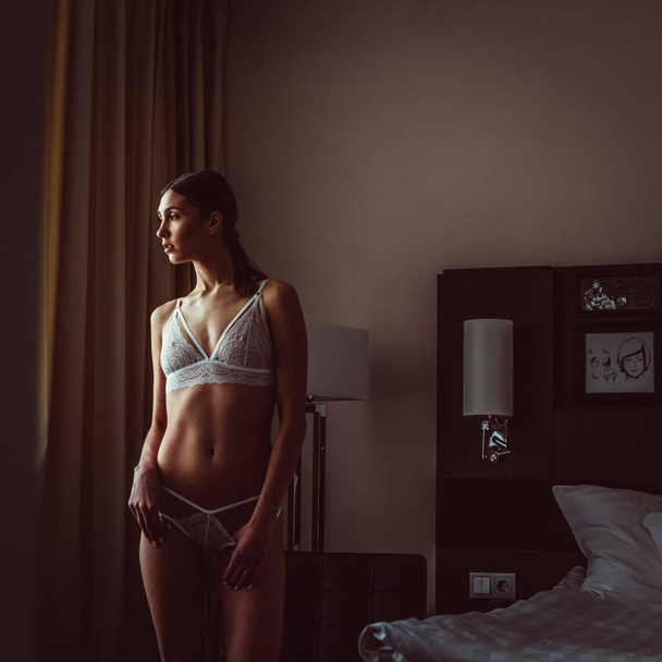 Young beautiful tall girl model half-naked in beautiful lingerie in a hotel room - Photo, image