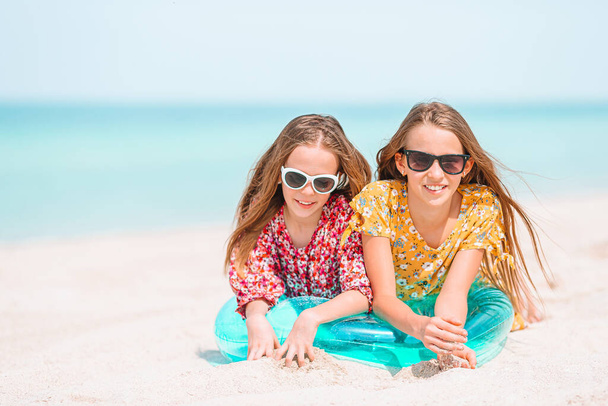 Little happy funny girls have a lot of fun at tropical beach playing together. - Photo, Image