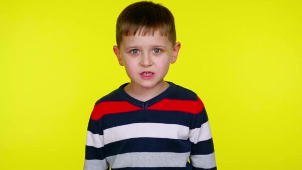 Verwirrter kleiner Junge knurrt auf gelbem Hintergrund mit Kopierraum in die Kamera - Filmmaterial, Video
