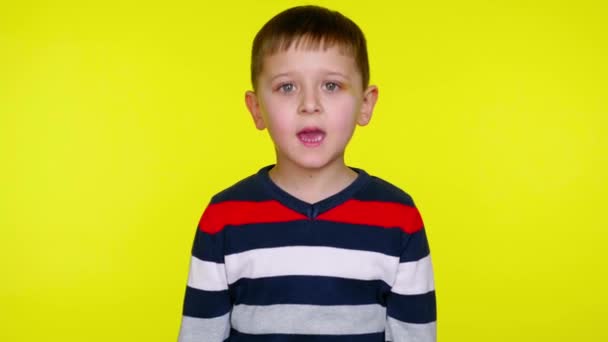 Serious little child boy in a colorful sweater says yes on a yellow background - Footage, Video