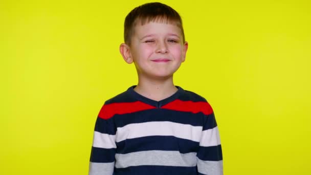 Kisgyerek fiú mosolyog, és pislog egy szemet a sárga háttér másolási hely - Felvétel, videó