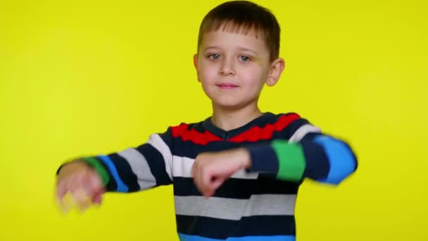 Fröhlicher kleiner Junge wendet sich der Kamera zu, verschränkt die Arme über der Brust und lächelt - Filmmaterial, Video