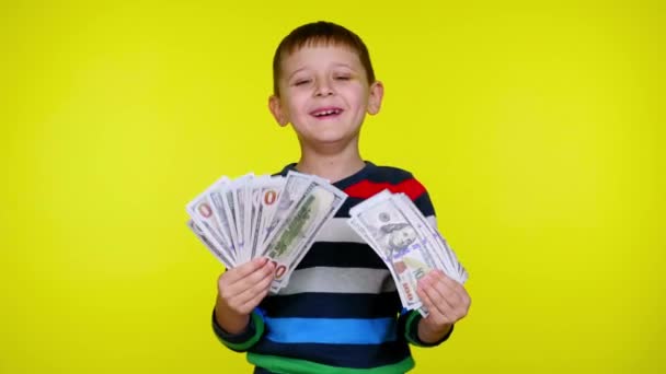 Gazdag gyerek fiú integet egy rajongó a pénz a kezében sárga háttér - Felvétel, videó