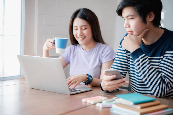 Junge asiatische Paare diskutieren zusammen und tippen am Computer während des Arbeitstages im Homeoffice. Arbeiten von zu Hause aus - Foto, Bild