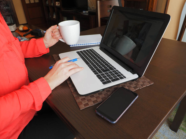 Γυναίκα που εργάζεται από το σπίτι με ένα φορητό υπολογιστή, ένα κινητό τηλέφωνο. - Φωτογραφία, εικόνα