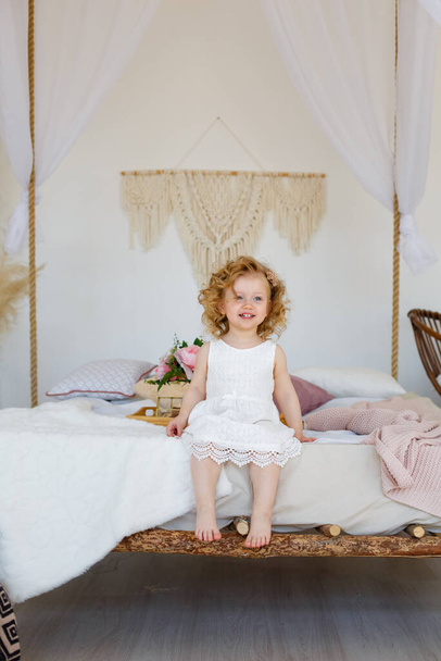 Cute adorable baby girl in a white bed. Morning time. Relax time. Baby child playful. Bed time. Playfulness. Happy lovely baby playing in bed - Foto, Imagen
